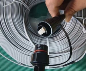 Demonstrate connector details for technical specs and installation guides. Hand displaying black SC/APC and FastConnect fiber optic connectors from gray cable coil.