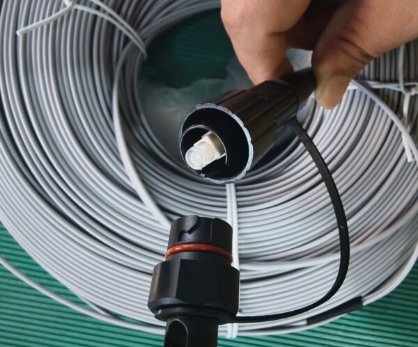 Demonstrate connector details for technical specs and installation guides. Hand displaying black SC/APC and FastConnect fiber optic connectors from gray cable coil.