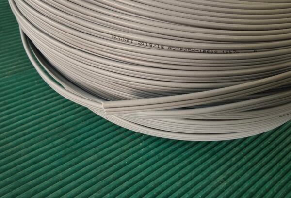 Showcase the coiled cable with manufacturing label for inventory overview. Gray coiled fiber optic cable on green surface showing HUAMET 2019/12 GYJXFCH-1B6a2 label.